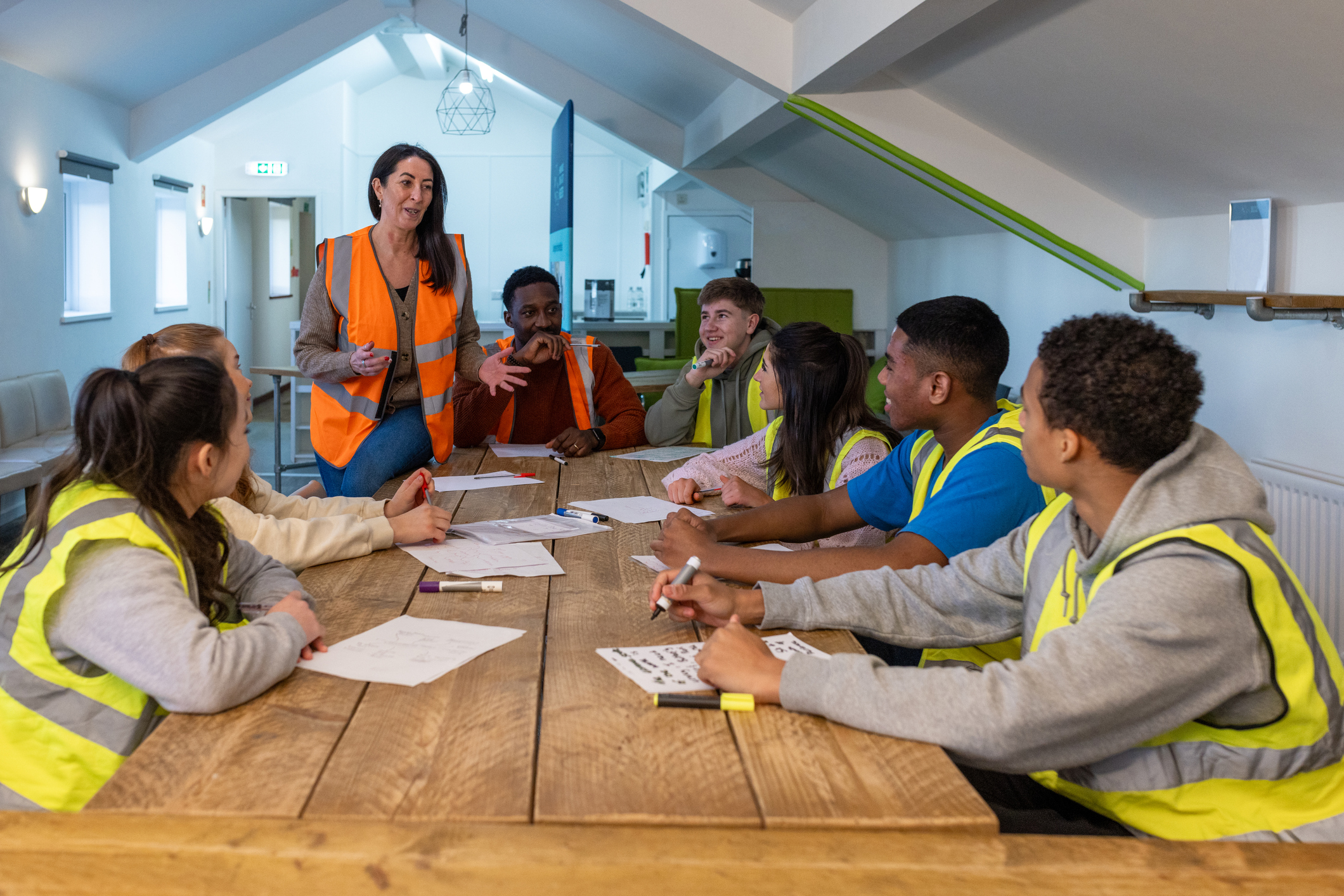  A team in safety vests meeting at a boardroom table.