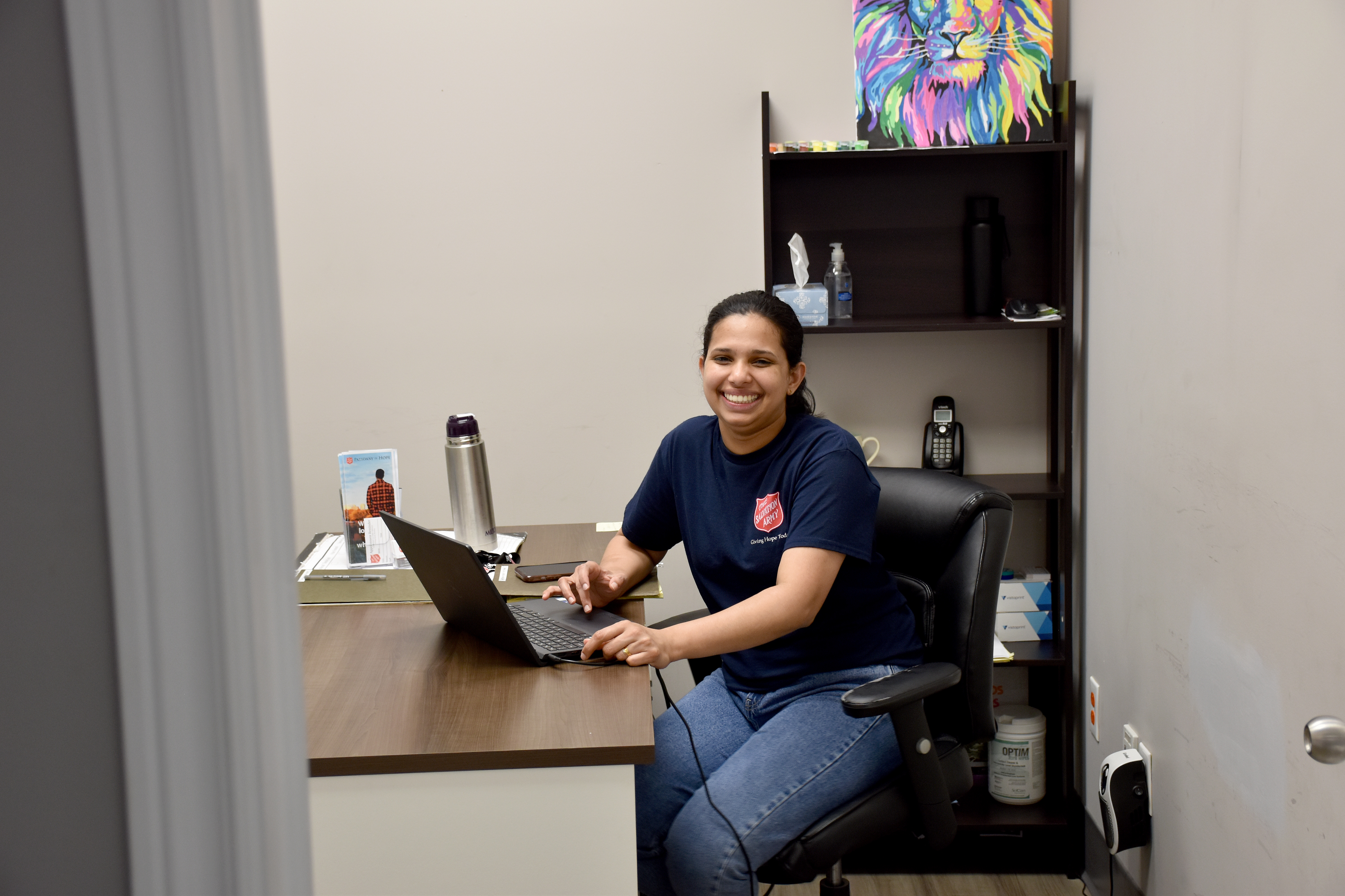 A Salvation Army manager sitting at a laptop and smiling. 