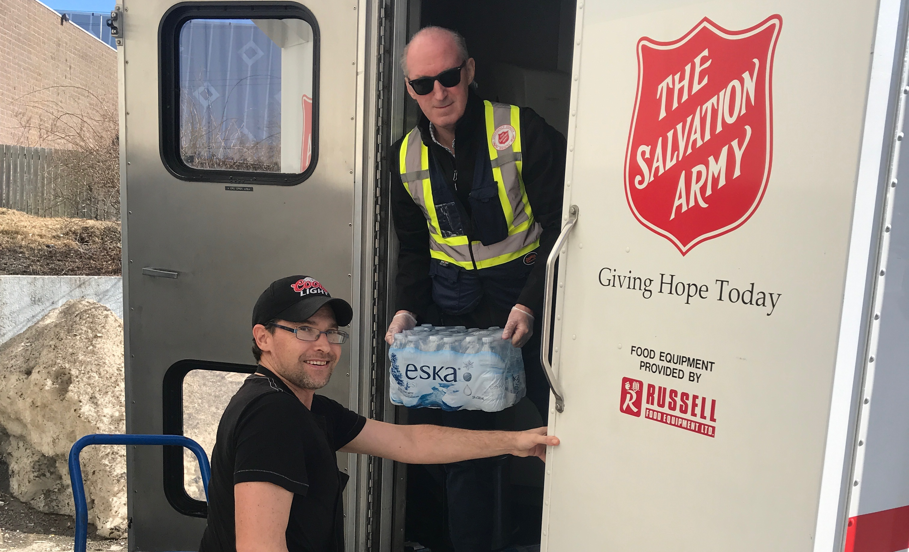 A picture of two EDS workers unloading water from the back of an EDS truck.